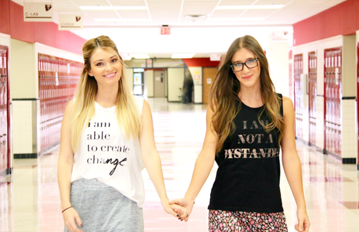 The Kind Campaign founders Lauren Parsekian and Molly Stroud hold hands in a school hallway.